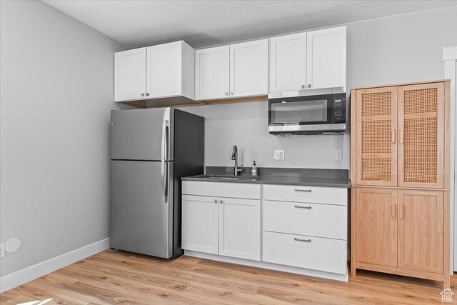 10262 N Yorkshire Cir, Highland, UT 84003 - kitchen featuring appliances with stainless steel finishes, dark countertops, light wood-type flooring, and white cabinetry
