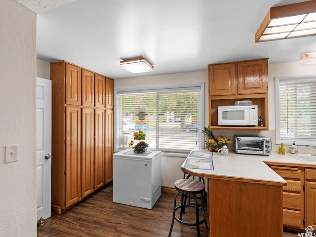 1034 E 1st St S, Ogden, UT 84404 - kitchen featuring white microwave, fridge, a peninsula, a breakfast bar area, and dark wood-type flooring