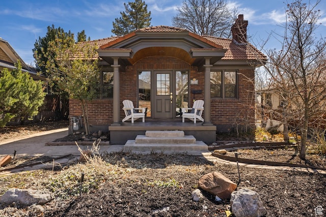 1444 E Sherman Ave, Salt Lake City, UT 84105 - view of front of property featuring brick siding, a porch, a tiled roof, and a chimney