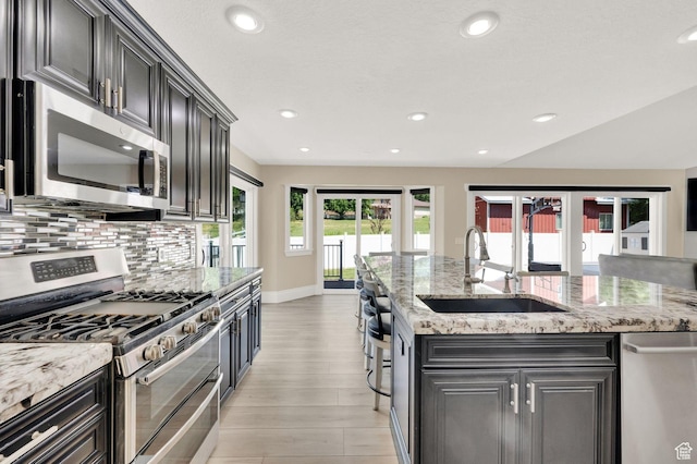 1788 N 925 E, North Ogden, UT 84414 - kitchen featuring appliances with stainless steel finishes, tasteful backsplash, light wood-type flooring, recessed lighting, and light stone countertops