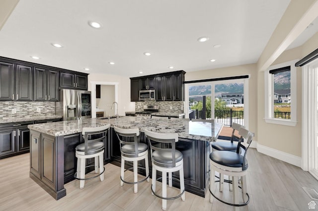 1788 N 925 E, North Ogden, UT 84414 - kitchen featuring appliances with stainless steel finishes, backsplash, a large island with sink, light wood finished floors, and recessed lighting