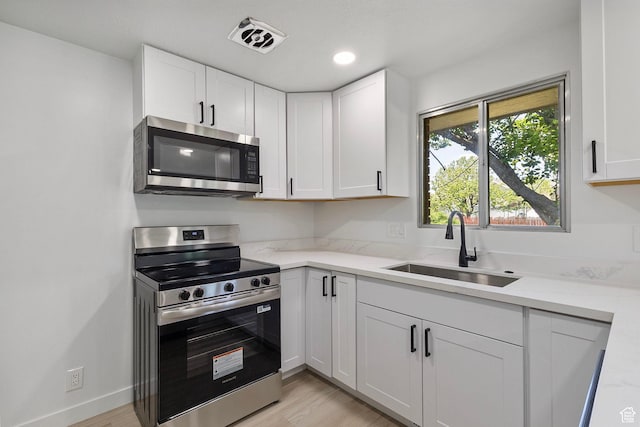 5600 S Ralph Dr, Taylorsville, UT 84129 - kitchen featuring stainless steel appliances, white cabinetry, light wood finished floors, and recessed lighting