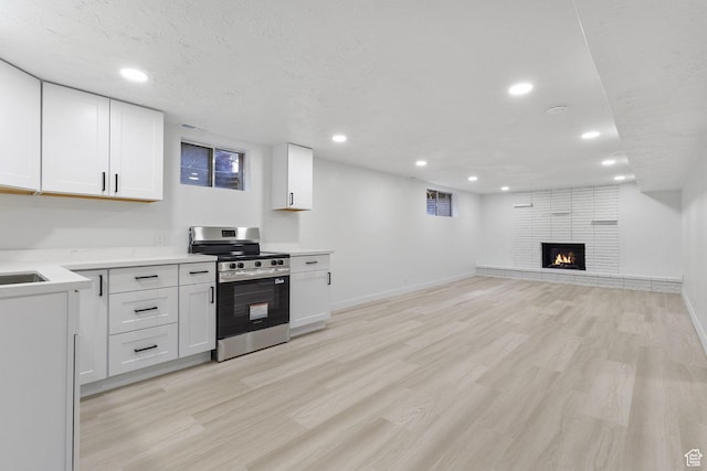 5600 S Ralph Dr, Taylorsville, UT 84129 - kitchen featuring stainless steel electric stove, white cabinets, light countertops, light wood-type flooring, and recessed lighting