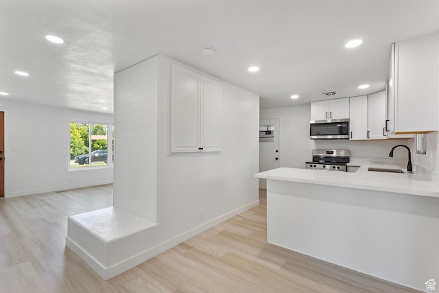 5600 S Ralph Dr, Taylorsville, UT 84129 - kitchen featuring stainless steel appliances, recessed lighting, light countertops, light wood finished floors, and white cabinets