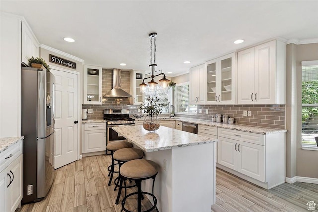 7258 S Mel Helen Way, West Jordan, UT 84084 - kitchen with stainless steel appliances, wall chimney exhaust hood, white cabinets, a breakfast bar, and tasteful backsplash