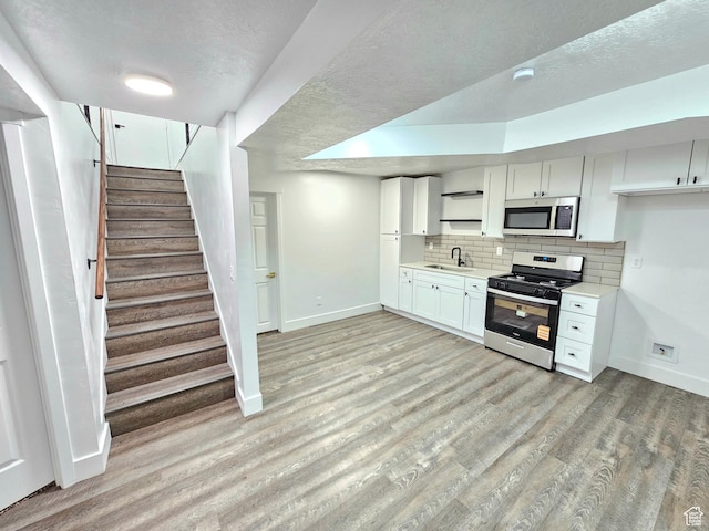 3797 S Armoridge Dr, Magna, UT 84044 - kitchen with appliances with stainless steel finishes, light countertops, open shelves, white cabinets, and light wood-style flooring