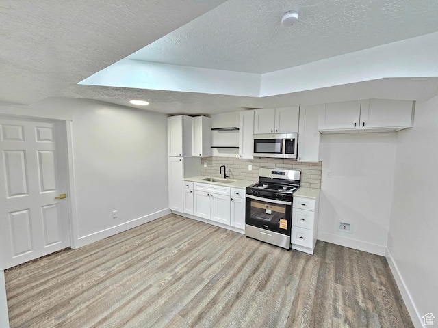 3797 S Armoridge Dr, Magna, UT 84044 - kitchen featuring stainless steel appliances, a textured ceiling, light wood-style flooring, decorative backsplash, and light countertops