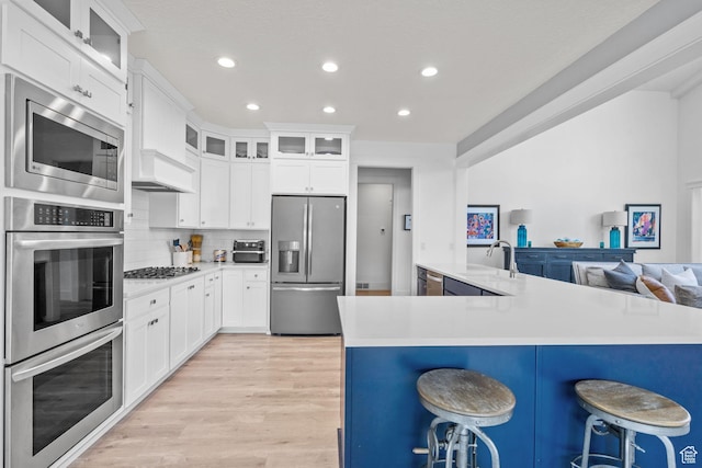 11571 S Skyward Rd W, South Jordan, UT 84009 - kitchen featuring stainless steel appliances, a kitchen bar, recessed lighting, light wood-style floors, and light countertops