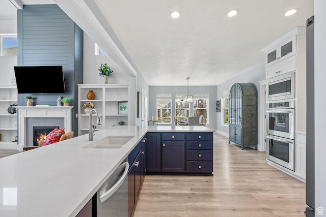 11571 S Skyward Rd W, South Jordan, UT 84009 - kitchen featuring appliances with stainless steel finishes, open floor plan, light wood-type flooring, light countertops, and a glass covered fireplace