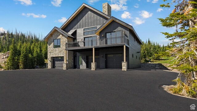 926 E Autumn Dr, Brian Head, UT 84719 - view of front of home featuring stone siding, an attached garage, a chimney, a balcony, and board and batten siding