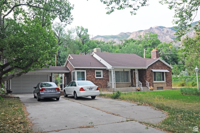 1160 E 12th St S, Ogden, UT 84404 - ranch-style house featuring a chimney, driveway, a mountain view, an attached garage, and brick siding