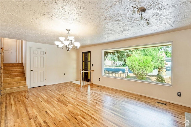 6690 S 1495 E, Cottonwood Heights, UT 84121 - unfurnished room with a chandelier, light wood-type flooring, healthy amount of natural light, and a textured ceiling