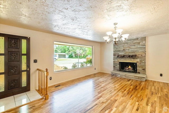 6690 S 1495 E, Cottonwood Heights, UT 84121 - unfurnished living room with wood finished floors, a chandelier, a textured ceiling, and a stone fireplace