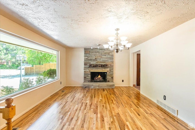6690 S 1495 E, Cottonwood Heights, UT 84121 - unfurnished living room featuring light wood-type flooring, a chandelier, a stone fireplace, and a textured ceiling