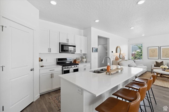 1128 E Bearing Dr S, Saratoga Springs, UT 84045 - kitchen featuring appliances with stainless steel finishes, open floor plan, a breakfast bar area, wood finished floors, and a textured ceiling
