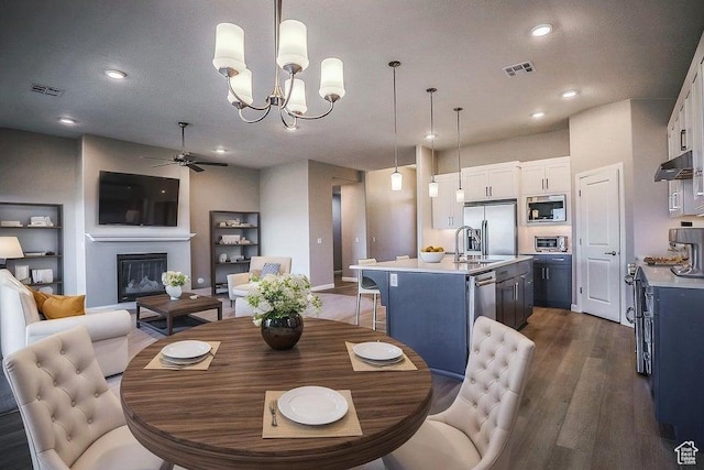 621 N Sage Hen Dr, Washington, UT 84780 - dining area with a ceiling fan, dark wood-style flooring, a chandelier, a glass covered fireplace, and recessed lighting