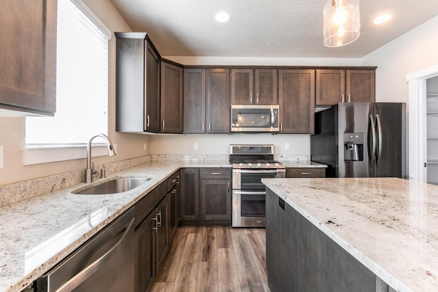 4567 W Breezy Meadow Dr, Herriman, UT 84096 - kitchen featuring stainless steel appliances, light wood finished floors, dark brown cabinets, light stone countertops, and pendant lighting
