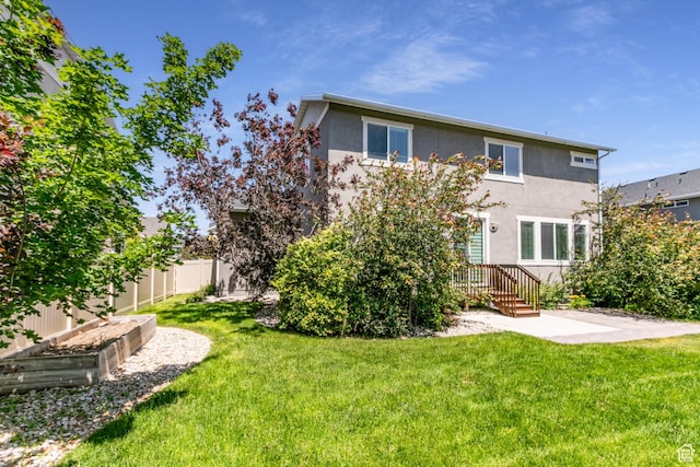 4567 W Breezy Meadow Dr, Herriman, UT 84096 - rear view of property featuring stucco siding, a patio, and a vegetable garden