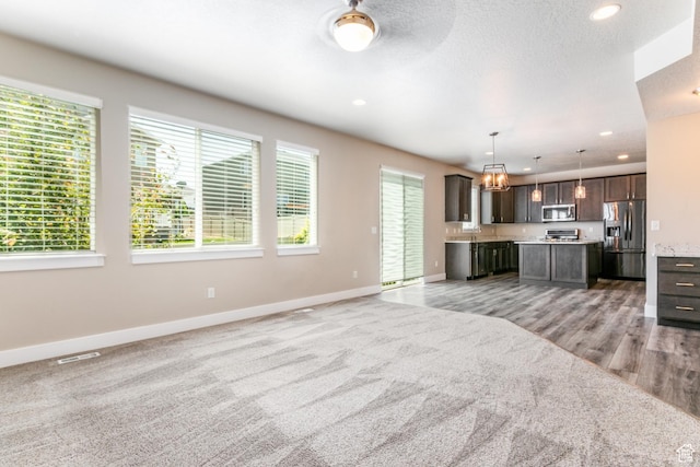 4567 W Breezy Meadow Dr, Herriman, UT 84096 - unfurnished living room with light colored carpet, recessed lighting, light wood-type flooring, and a chandelier