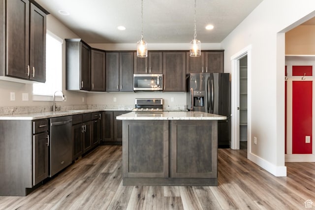 4567 W Breezy Meadow Dr, Herriman, UT 84096 - kitchen with stainless steel appliances, dark brown cabinetry, light wood finished floors, a center island, and recessed lighting