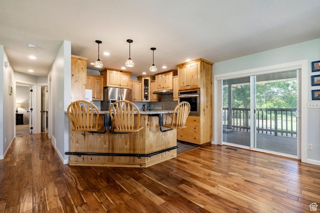 8871 S 100 E, Paradise, UT 84328 - kitchen with stainless steel appliances, light brown cabinets, dark wood-style flooring, a breakfast bar, and recessed lighting