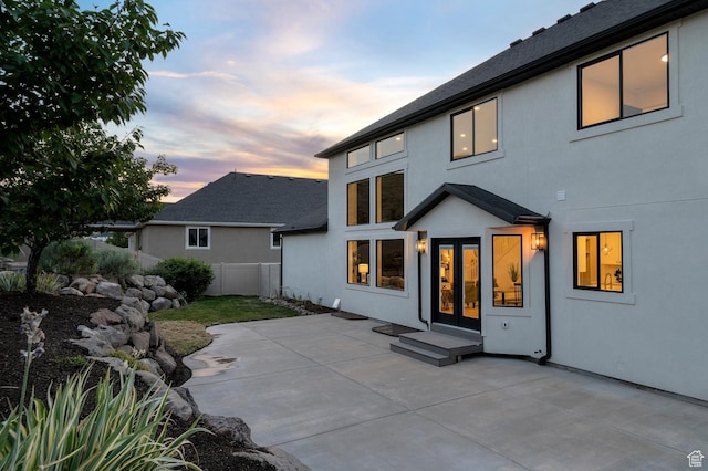 6809 W Vista Springs Dr, Herriman, UT 84096 - back of house at dusk with a patio, stucco siding, and french doors