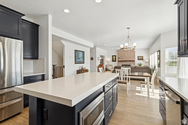 319 S 300 E, Midway, UT 84049 - kitchen featuring appliances with stainless steel finishes, light countertops, light wood-type flooring, a center island, and open floor plan