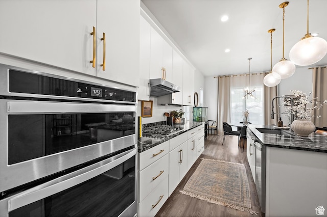 4753 W Mossley Dr, Herriman, UT 84096 - kitchen with appliances with stainless steel finishes, dark wood-style floors, under cabinet range hood, white cabinets, and decorative light fixtures