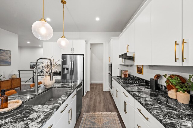4753 W Mossley Dr, Herriman, UT 84096 - kitchen with under cabinet range hood, stainless steel appliances, dark stone countertops, decorative light fixtures, and recessed lighting