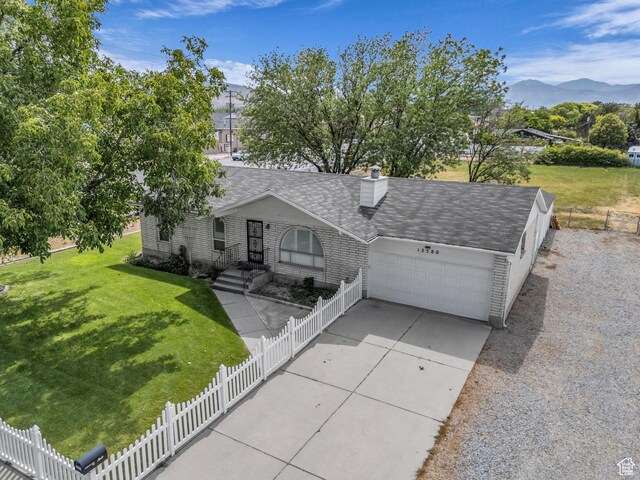 12580 S Janice Dr, Riverton, UT 84065 - view of front facade with a garage, a mountain view, a shingled roof, brick siding, and concrete driveway