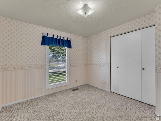 12580 S Janice Dr, Riverton, UT 84065 - unfurnished bedroom featuring wallpapered walls, a closet, a textured ceiling, and carpet