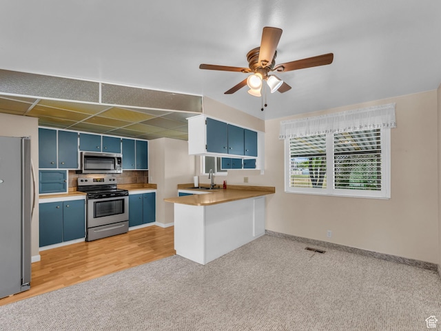 12580 S Janice Dr, Riverton, UT 84065 - kitchen with appliances with stainless steel finishes, blue cabinetry, a ceiling fan, light colored carpet, and a peninsula