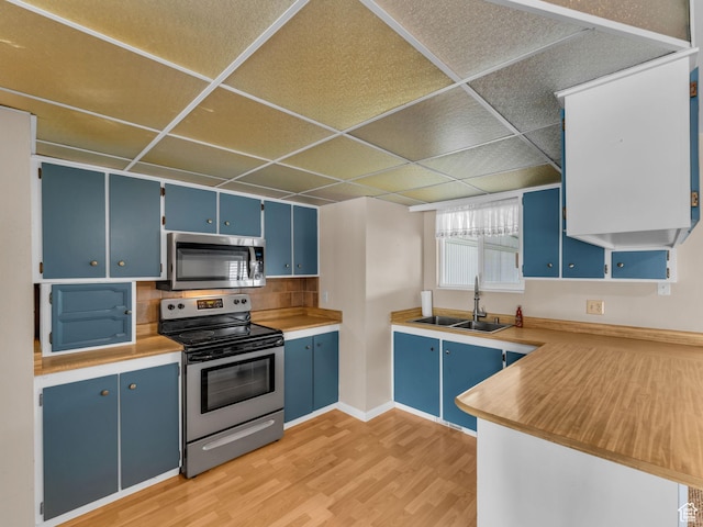 12580 S Janice Dr, Riverton, UT 84065 - kitchen with stainless steel appliances, blue cabinets, light wood finished floors, a drop ceiling, and backsplash
