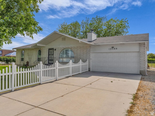 12580 S Janice Dr, Riverton, UT 84065 - ranch-style house with brick siding, a garage, driveway, a fenced front yard, and a chimney