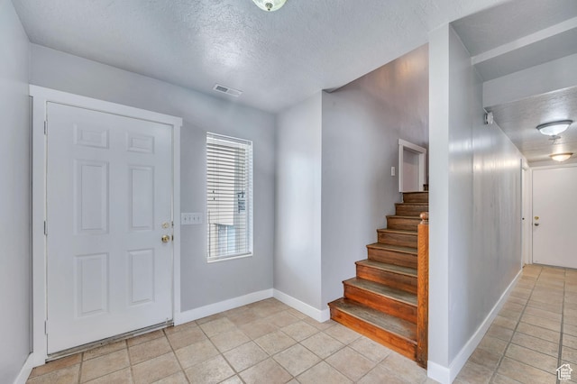 4940 S Atwood Blvd, Murray, UT 84107 - foyer entrance with a textured ceiling, light tile patterned floors, and stairway