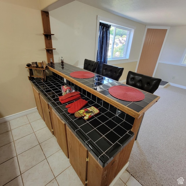 5272 S 1035 E, South Ogden, UT 84403 - kitchen featuring tile counters, a peninsula, light tile patterned floors, and brown cabinetry