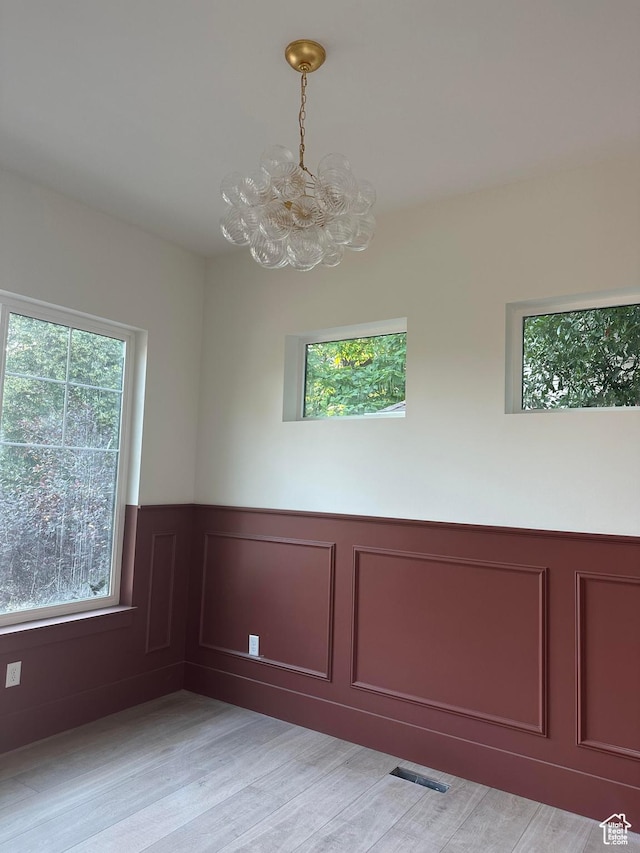 1361 S Lincoln St, Salt Lake City, UT 84105 - empty room featuring a chandelier, wainscoting, a decorative wall, and light wood-style flooring