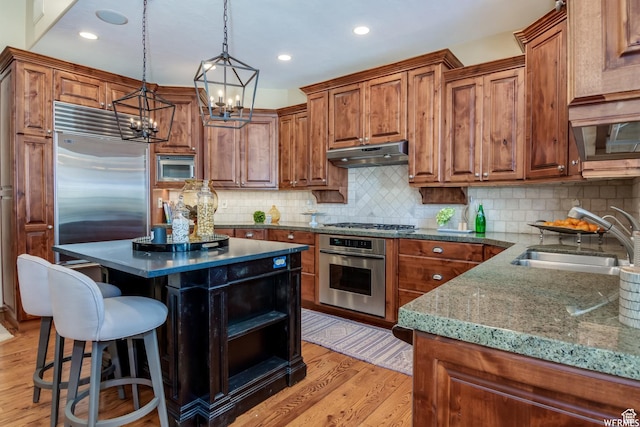 1321 E Farm Dr, Murray, UT 84117 - kitchen with built in appliances, under cabinet range hood, brown cabinets, a chandelier, and recessed lighting