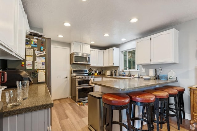 24725 N 11925 E, Fairview, UT 84629 - kitchen with stainless steel appliances, a peninsula, white cabinets, light wood-type flooring, and recessed lighting