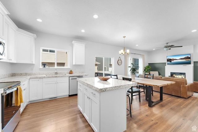 4925 E Breezy Patch Rd, Eagle Mountain, UT 84005 - kitchen featuring appliances with stainless steel finishes, ceiling fan, light wood-style floors, a glass covered fireplace, and recessed lighting