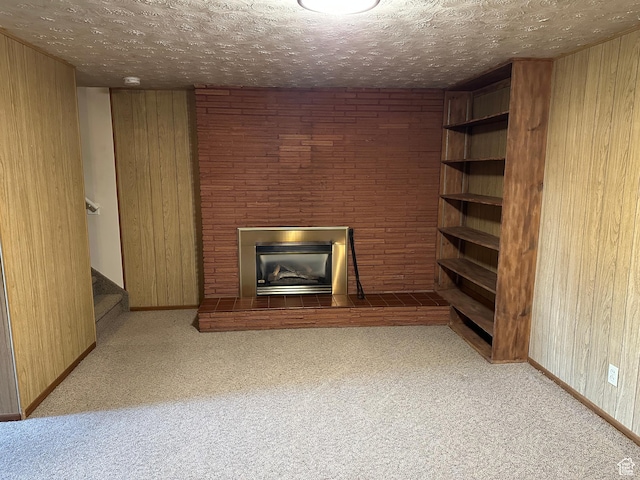 487 Highland Blvd, Brigham City, UT 84302 - unfurnished living room with carpet flooring, a fireplace with raised hearth, wood walls, stairway, and a textured ceiling