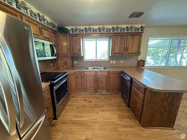 487 Highland Blvd, Brigham City, UT 84302 - kitchen with appliances with stainless steel finishes, a peninsula, backsplash, light wood-type flooring, and light countertops