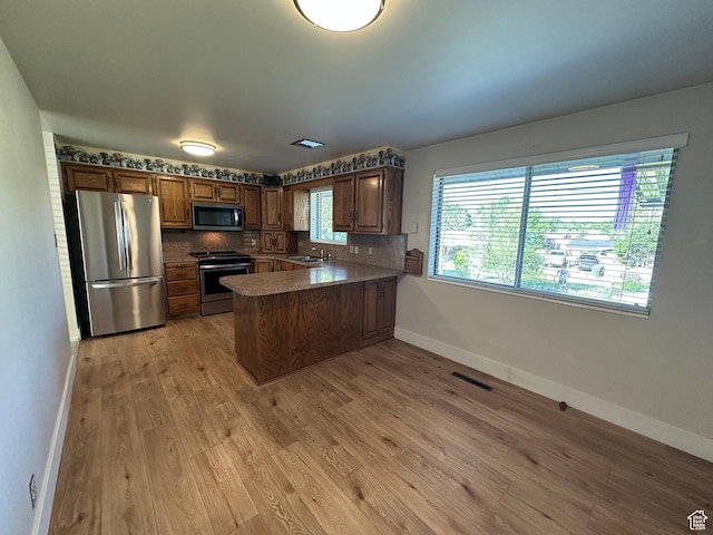 487 Highland Blvd, Brigham City, UT 84302 - kitchen featuring appliances with stainless steel finishes, a peninsula, light wood-type flooring, and decorative backsplash