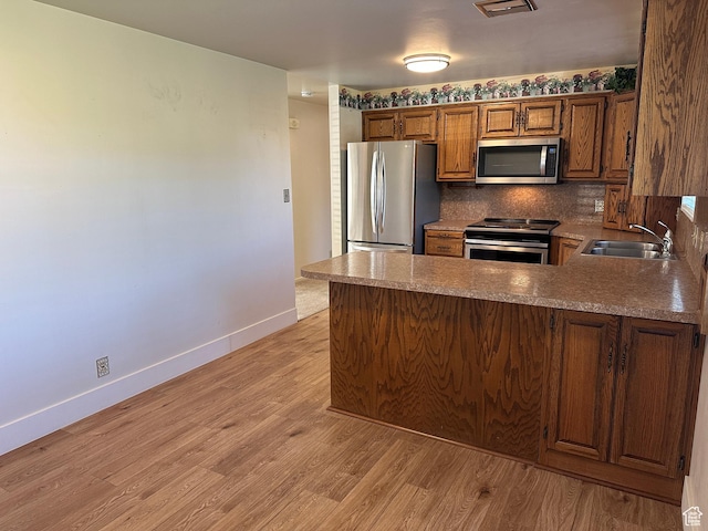 487 Highland Blvd, Brigham City, UT 84302 - kitchen with stainless steel appliances, a peninsula, light wood finished floors, brown cabinetry, and tasteful backsplash