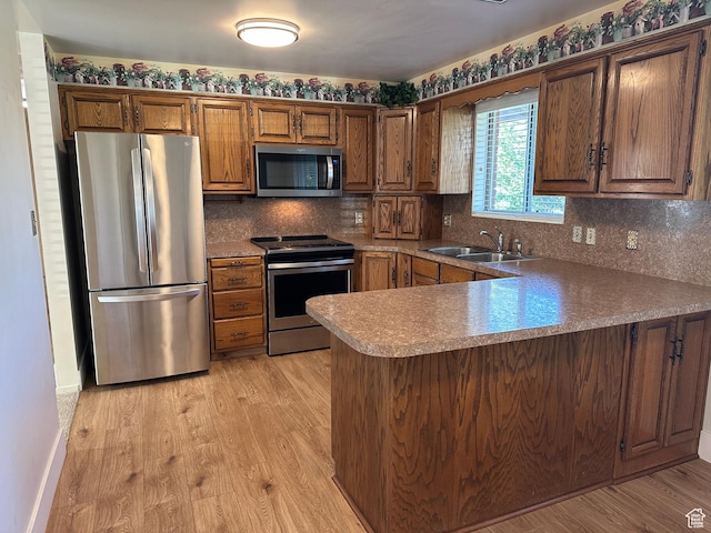 487 Highland Blvd, Brigham City, UT 84302 - kitchen with appliances with stainless steel finishes, light wood finished floors, a peninsula, and decorative backsplash