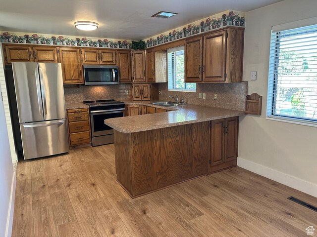 487 Highland Blvd, Brigham City, UT 84302 - kitchen with appliances with stainless steel finishes, a peninsula, decorative backsplash, and light wood-style flooring