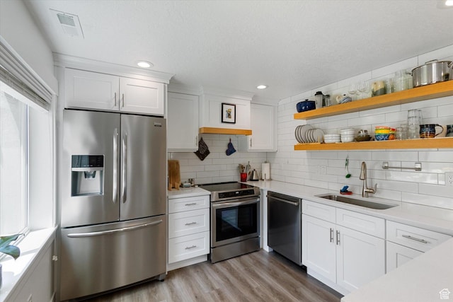 605 W 1660 S, Provo, UT 84601 - kitchen featuring appliances with stainless steel finishes, light countertops, decorative backsplash, white cabinetry, and light wood-type flooring