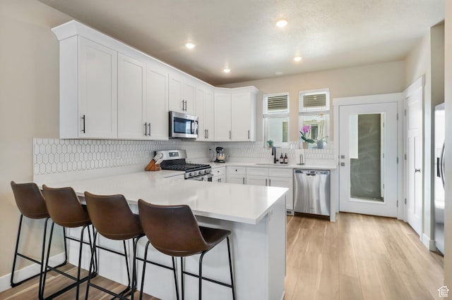 1017 S 2740 E, Spanish Fork, UT 84660 - kitchen featuring appliances with stainless steel finishes, a peninsula, white cabinets, light countertops, and a breakfast bar