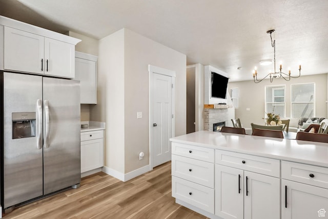 1017 S 2740 E, Spanish Fork, UT 84660 - kitchen featuring stainless steel refrigerator with ice dispenser, a chandelier, open floor plan, light wood finished floors, and white cabinetry