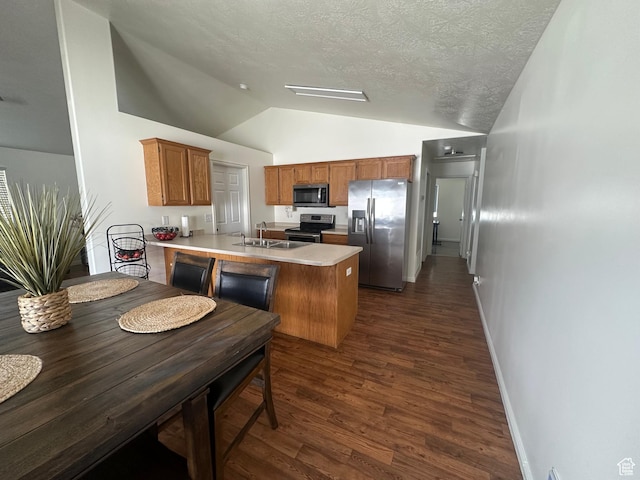 1485 N Monroe Blvd E, Ogden, UT 84404 - kitchen featuring appliances with stainless steel finishes, a peninsula, vaulted ceiling, dark wood-type flooring, and brown cabinetry